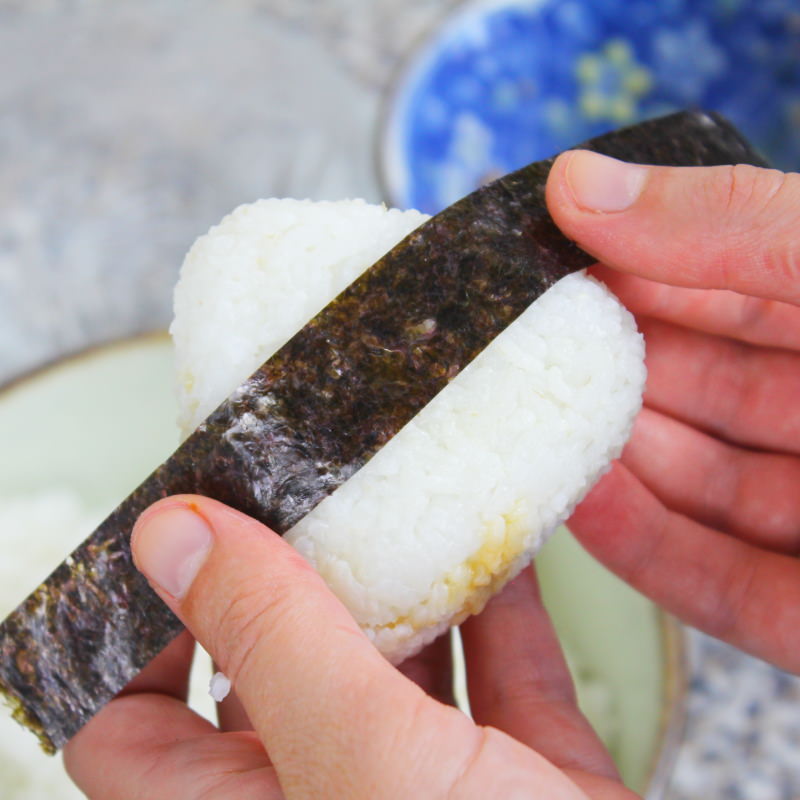 Tsukudani Onigiri mit Kombu Schritt 8 mit Nori umwickeln